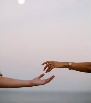 Hands reaching for each other at dusk