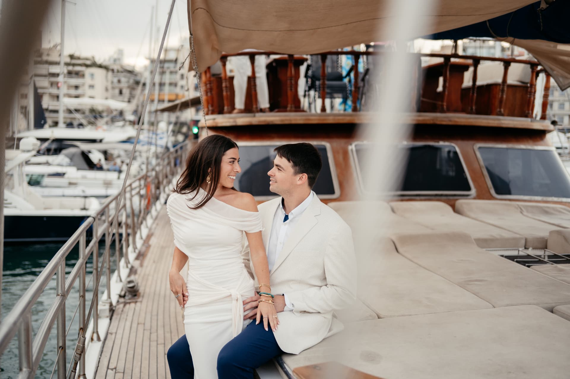 A couple smiling at each other aboard a boat in the harbour