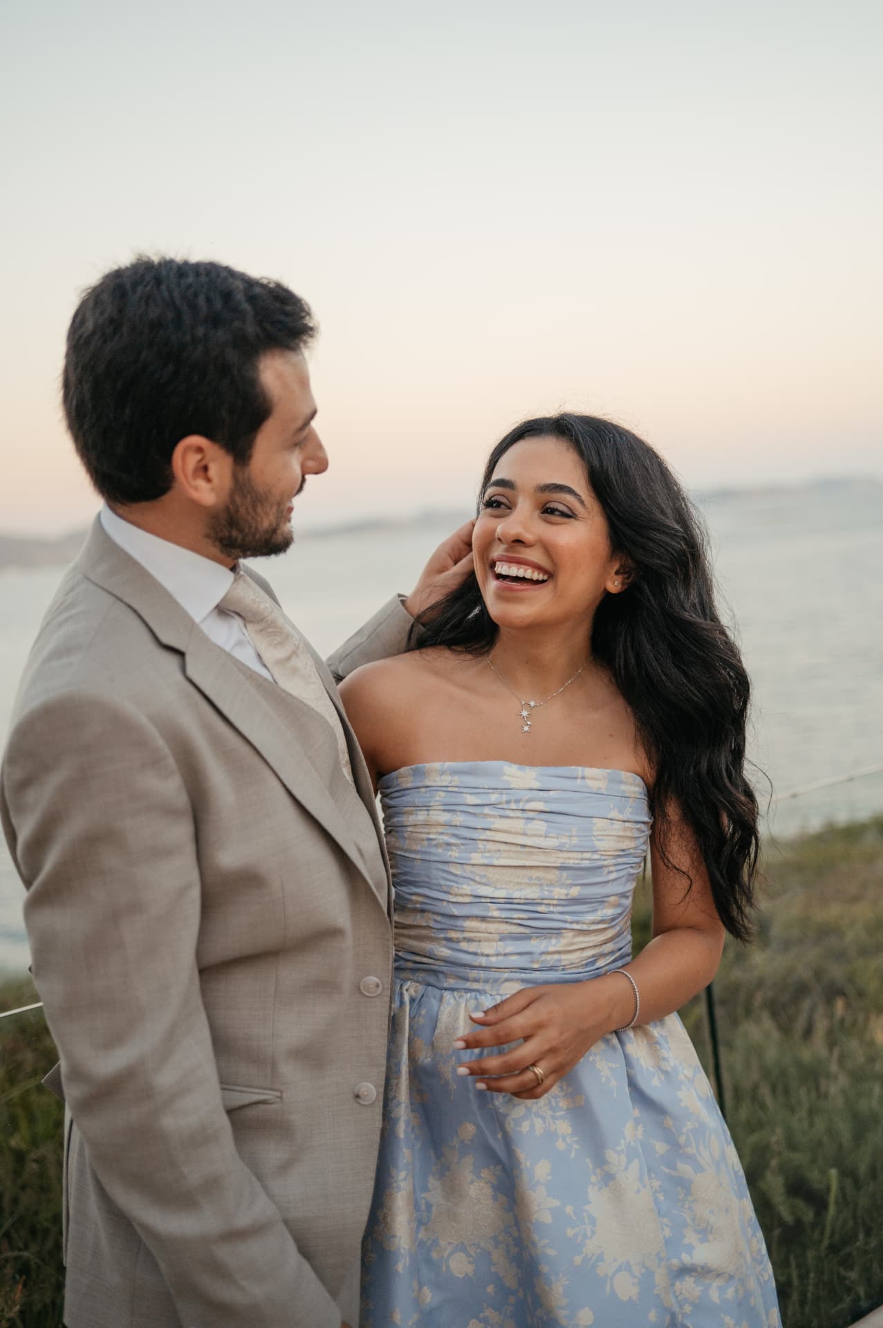 A couple laughing together above the sea at dusk