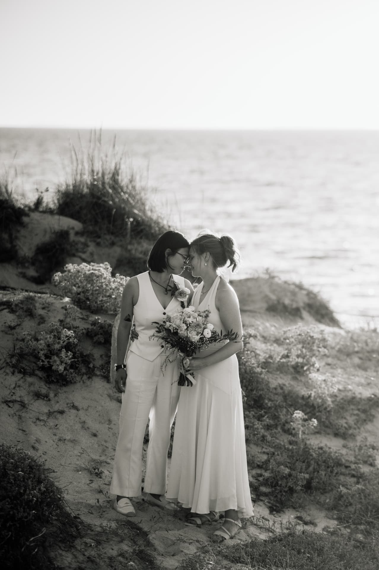 Two brides forehead to forehead by the sea